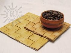 a bowl of coffee beans sitting on top of a bamboo placemat and napkins