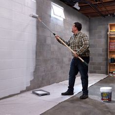 a man holding a paint roller in front of a wall