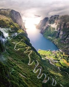 an aerial view of a winding road in the middle of a mountain range with a lake below