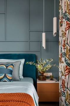 a bedroom with blue walls and orange bedding in the foreground is a small table with flowers on it