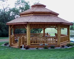 a wooden gazebo sitting on top of a lush green field