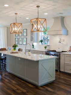 a large kitchen with an island in the middle and two pendant lights hanging from the ceiling