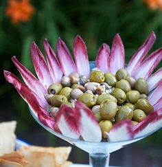 a glass bowl filled with olives and other food