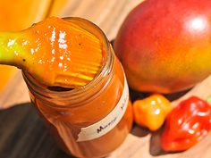 a jar filled with orange and yellow liquid next to some fruit on a table top