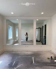 a woman standing in an empty room looking at her cell phone