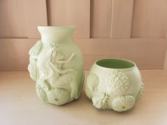 two green vases sitting next to each other on a table