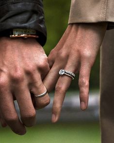 two people holding hands with wedding rings on their fingers and one wearing a ring in the other's hand