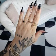 a woman's hand with black and white nail polish on it, holding up her ring