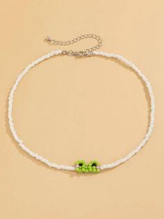 a white beaded bracelet with green beads and two small flowers on the clasps