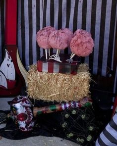 there are three pink donuts sitting on top of a stack of hay and fake toothbrushes