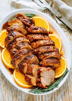 sliced pork and oranges on a white plate