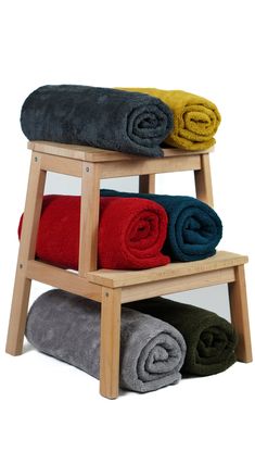 three towels stacked on top of each other in a wooden rack with two different colors