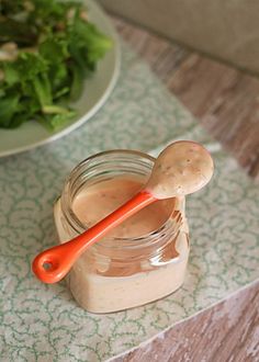 a jar filled with peanut butter next to a bowl of salad