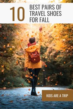 a woman walking down the road with her hand up in the air and leaves falling around her