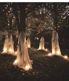 halloween decorations are lit up in the yard at night, with ghost - like lights