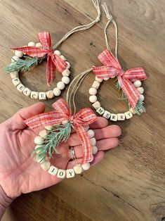 someone is holding two christmas wreaths made out of wood beads