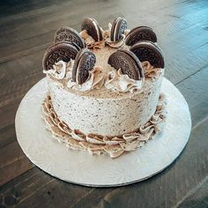 an oreo cookies and cream cake on a white plate with wood floor in the background