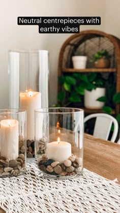 three clear glass vases filled with rocks and lit candles on top of a wooden table