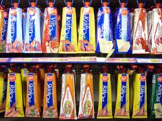 many different types of juices are on display in a grocery store, including orange, blue and yellow