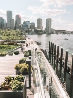 people are walking on the boardwalk next to the water