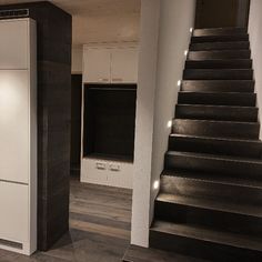 an empty room with stairs leading up to the second floor and white cabinets on either side