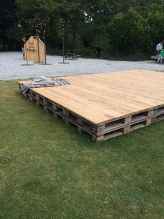 a large wooden platform sitting on top of a lush green field