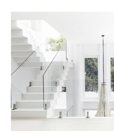 a room with white walls and stairs in the background, there is a large window on the far wall