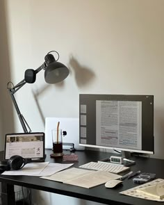 a desk with a monitor, keyboard and mouse on it in front of a lamp