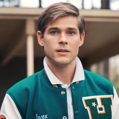 a young man in a green and white jacket is looking at the camera with an intense look on his face