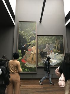 people are looking at paintings in an art gallery