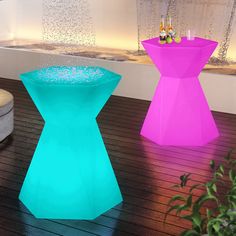 two colorful stools sitting on top of a wooden floor next to a potted plant