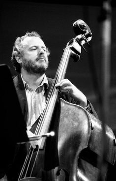 a man is playing an instrument in black and white photo with his hands on the strings