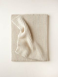 a white and beige striped blanket folded on top of a table next to a wall