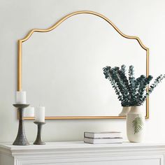 a vase with flowers and candles on a mantle in front of a white wall mirror