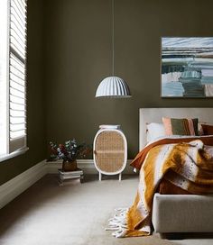 a bedroom with green walls and a bed covered in blankets, next to a painting on the wall