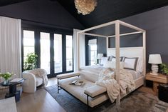 a bedroom with a canopy bed and white furniture on the floor next to two chairs