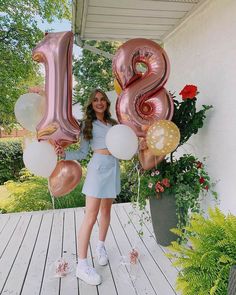 a woman standing on a porch with balloons in the shape of numbers