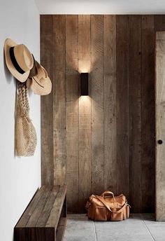 a brown bag sitting on top of a wooden bench next to a wall mounted light