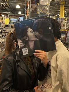 a woman holding up a record in front of her face and kissing the man's forehead