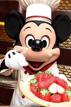 a mickey mouse holding a plate with strawberries on it