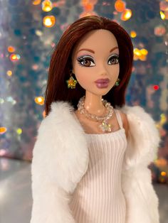 a barbie doll wearing a white sweater and fur coat with lights in the back ground behind her