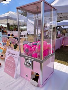 a pink gummy machine sitting on top of a table next to a white tent