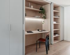 a room with some shelves and a chair in the corner, next to a desk