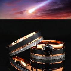 two wedding bands with black diamonds are shown in front of an image of the sky