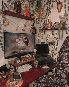 a computer desk with a laptop on it and lots of plants hanging from the wall