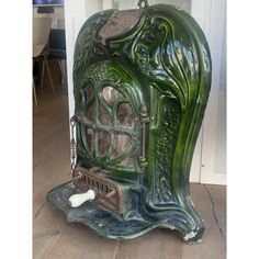 an old fashioned green stove sitting on top of a wooden floor