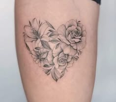 a heart shaped tattoo with flowers and leaves on the side of the thigh, in black and white