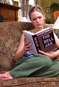 a woman sitting on a couch reading a book