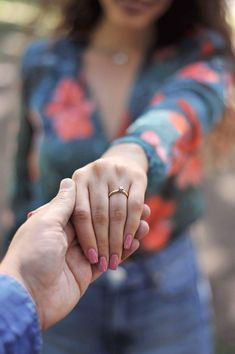 a woman holding the hand of a man who is wearing a wedding ring on his finger