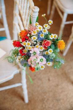 a bouquet of colorful flowers sitting on top of a white chair next to a railing